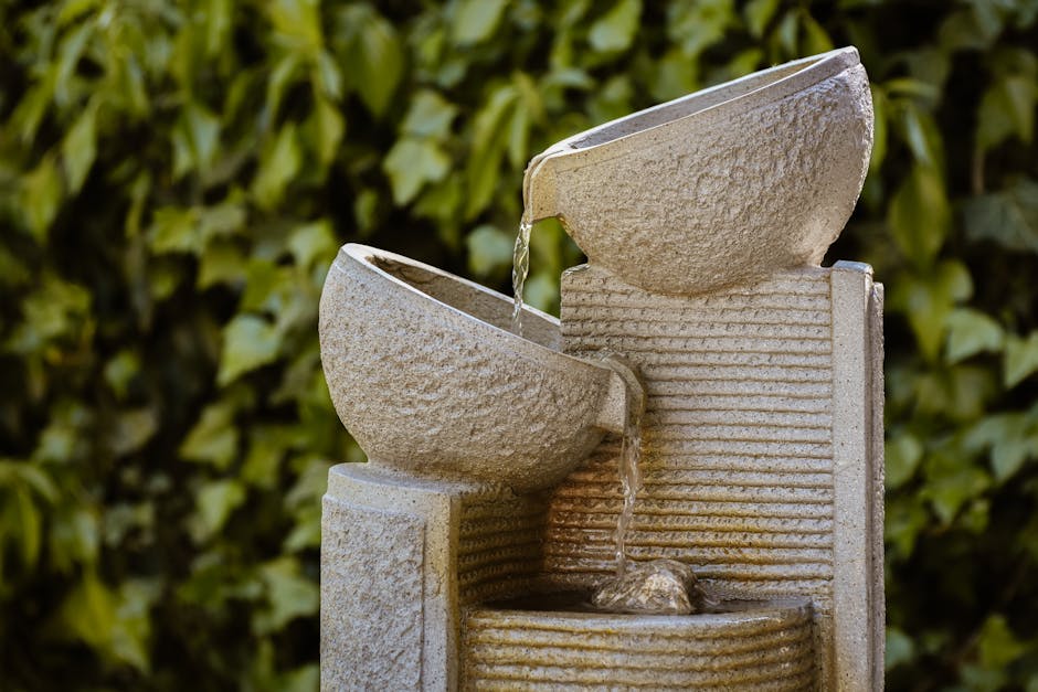 An elegant stone fountain with cascading water in a lush garden setting, providing a tranquil atmosphere.