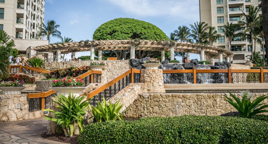 A stunning view of a tropical resort with lush gardens, stone architecture, and palm trees.