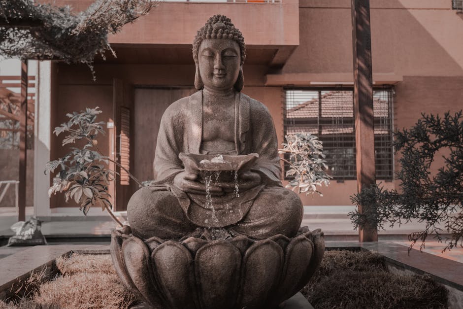 Peaceful Buddha statue with water fountain in a serene outdoor garden.